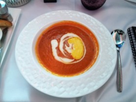 Roasted red pepper and tomato soup served in a covered bowl